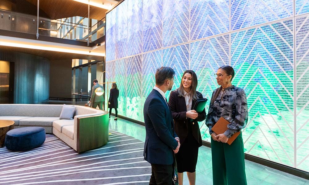 Three people speaking in office lobby