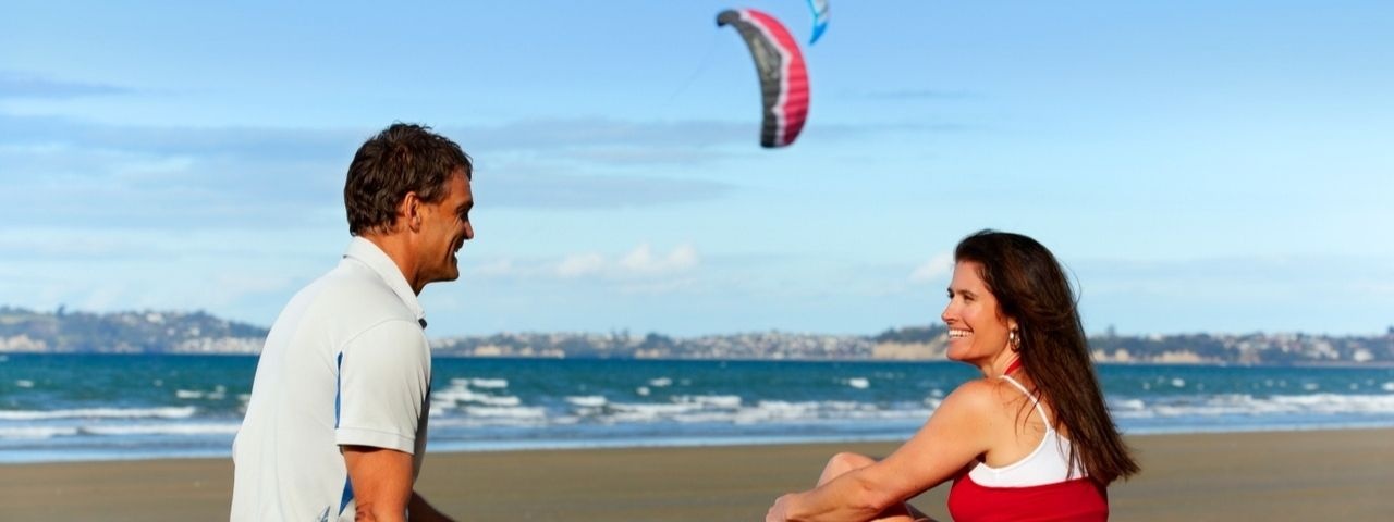 A male and female sitting on a beach in Auckland 
