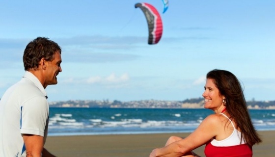 A male and female sitting on a beach in Auckland 